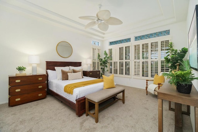 carpeted bedroom featuring a raised ceiling and ceiling fan