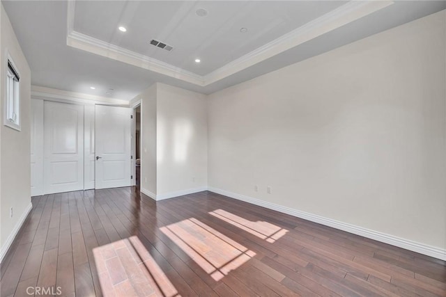 empty room featuring dark wood-type flooring and a raised ceiling