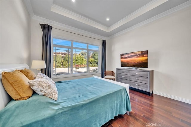 bedroom featuring dark hardwood / wood-style flooring, ornamental molding, and a tray ceiling