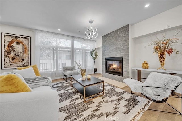 living room featuring an inviting chandelier, hardwood / wood-style floors, and a tile fireplace