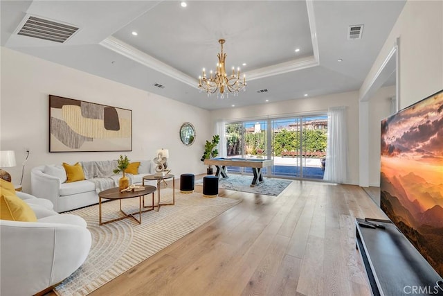 game room with billiards, a tray ceiling, light hardwood / wood-style flooring, ornamental molding, and a chandelier