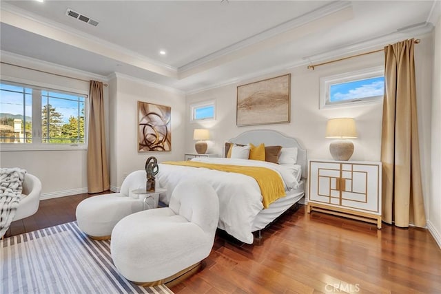 bedroom with hardwood / wood-style flooring, a tray ceiling, and crown molding