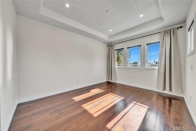 unfurnished room featuring dark wood-type flooring and a tray ceiling