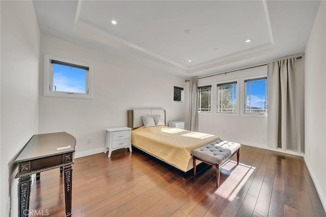 bedroom with multiple windows, dark hardwood / wood-style flooring, and a raised ceiling