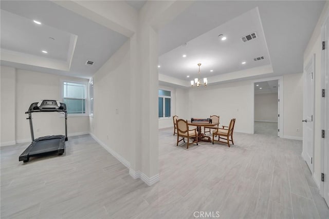 interior space featuring a raised ceiling, a notable chandelier, and light wood-type flooring