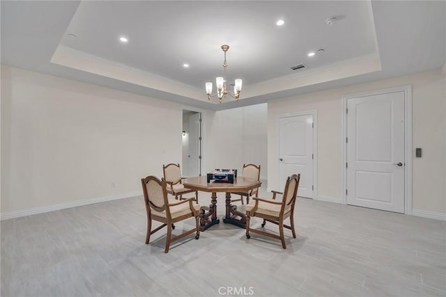 dining area with an inviting chandelier, light hardwood / wood-style flooring, and a tray ceiling