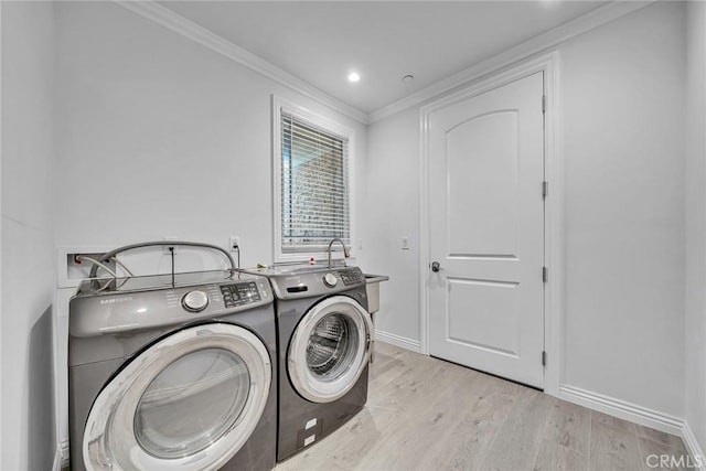 laundry area featuring light hardwood / wood-style flooring, ornamental molding, and washing machine and clothes dryer