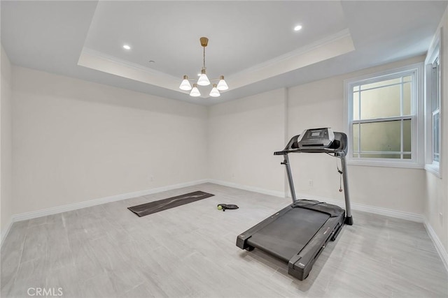 workout room with an inviting chandelier, crown molding, and a tray ceiling