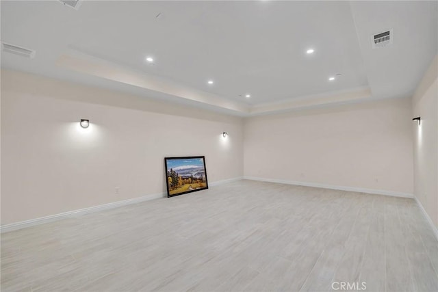 unfurnished living room with a tray ceiling and light hardwood / wood-style flooring