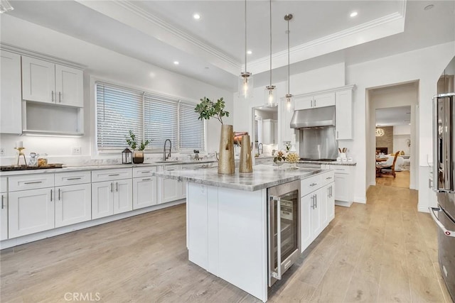 kitchen with decorative light fixtures, white cabinets, beverage cooler, and a tray ceiling