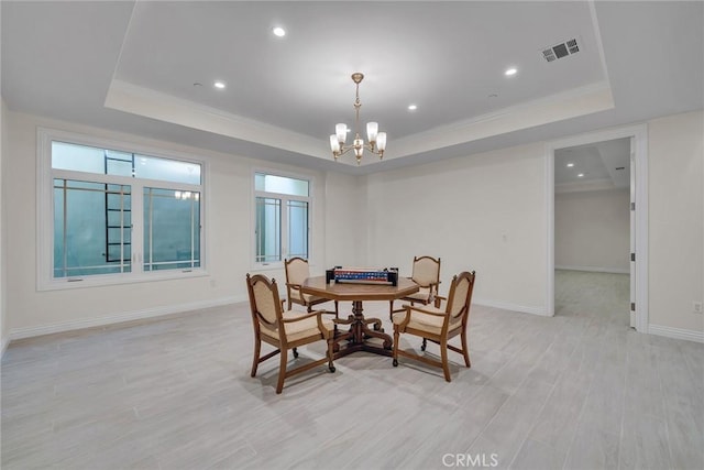 dining room featuring a raised ceiling, light wood-type flooring, crown molding, and a chandelier