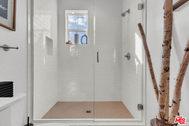 bathroom featuring a shower with shower door and toilet