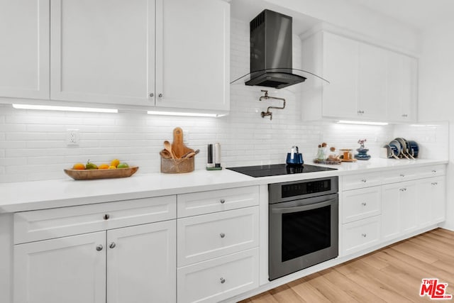 kitchen with white cabinetry, black electric stovetop, island range hood, and oven