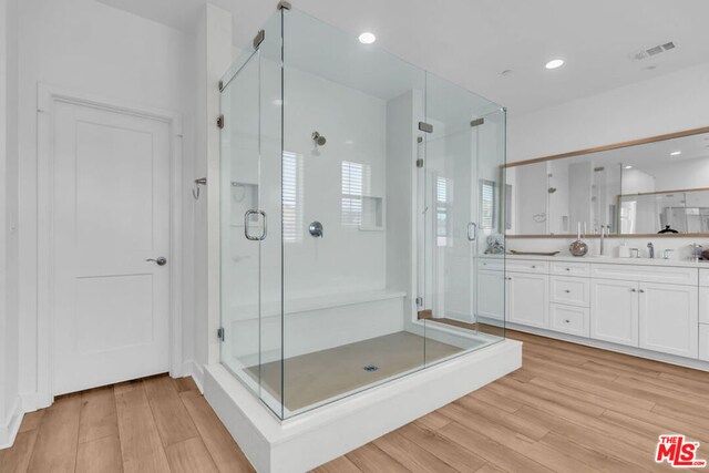 bathroom with hardwood / wood-style flooring, a shower with door, and vanity