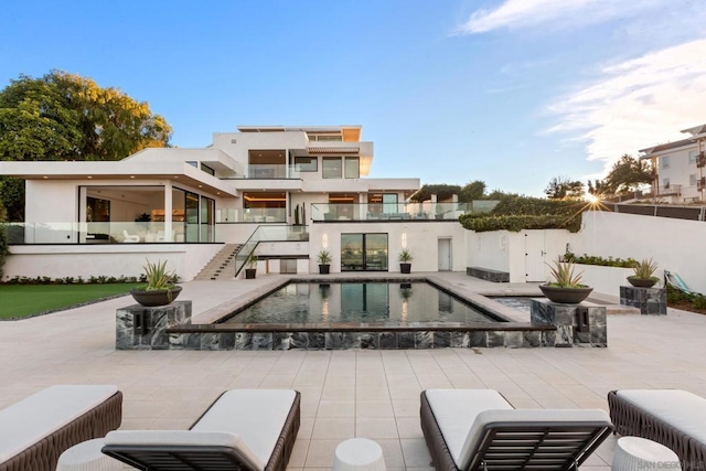 rear view of property featuring a fenced in pool and a patio