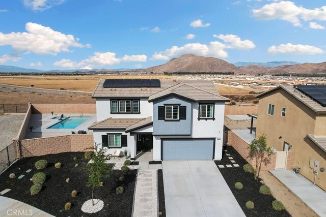 view of front property featuring a mountain view, solar panels, and a garage