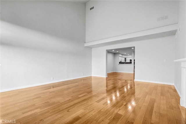 unfurnished living room featuring wood-type flooring and a high ceiling