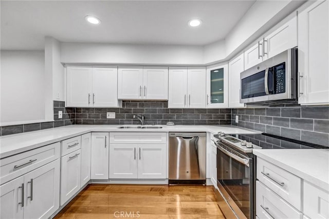 kitchen with white cabinets, sink, stainless steel appliances, and light hardwood / wood-style floors