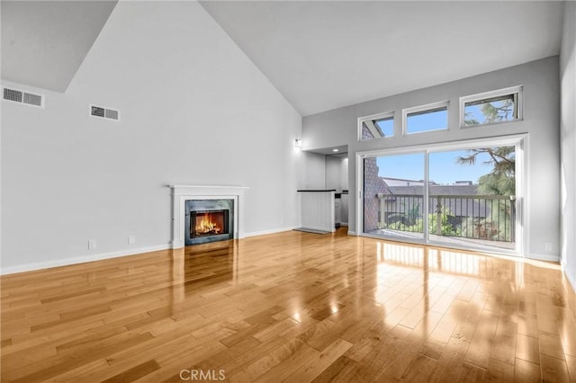 unfurnished living room with wood-type flooring and high vaulted ceiling