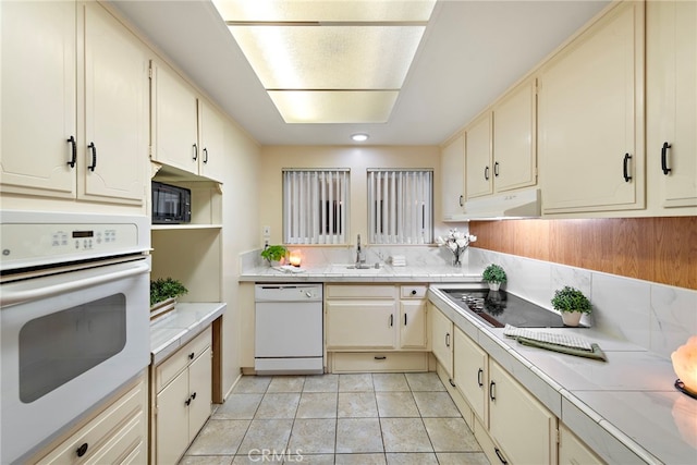 kitchen with sink, cream cabinets, black appliances, and light tile patterned flooring