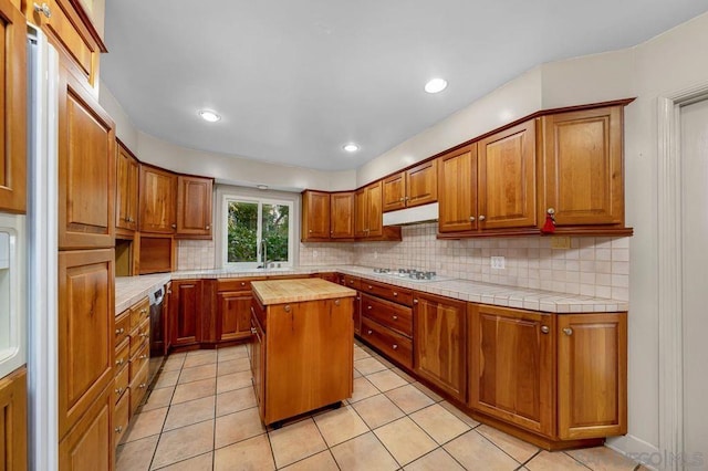 kitchen featuring dishwasher, light tile patterned floors, a center island, and butcher block counters