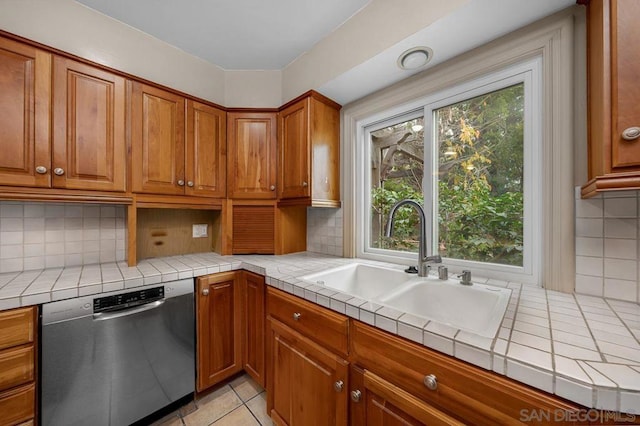 kitchen featuring tile countertops, stainless steel dishwasher, backsplash, and sink