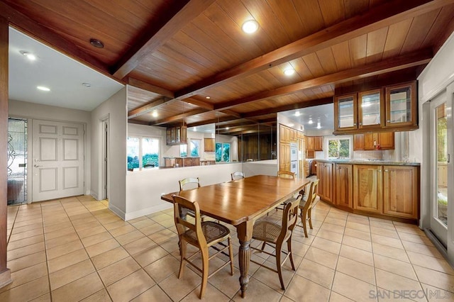 dining room with light tile patterned floors, wood ceiling, and beamed ceiling