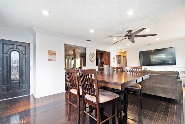 dining room with ceiling fan, dark hardwood / wood-style floors, crown molding, and a textured ceiling