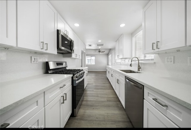 kitchen featuring white cabinets, dark hardwood / wood-style flooring, stainless steel appliances, sink, and ceiling fan