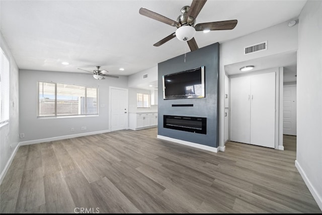 unfurnished living room with hardwood / wood-style flooring, a healthy amount of sunlight, ceiling fan, and a fireplace