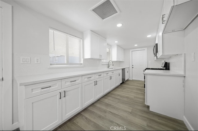 kitchen featuring visible vents, light wood-style floors, white cabinets, stainless steel appliances, and a sink