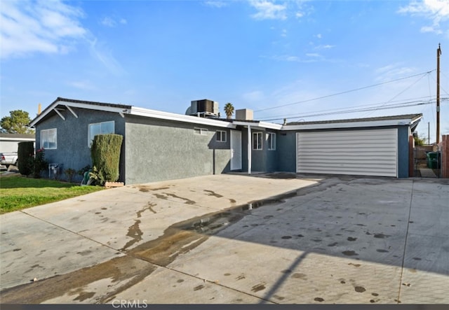 view of front of home with cooling unit, stucco siding, driveway, and a garage