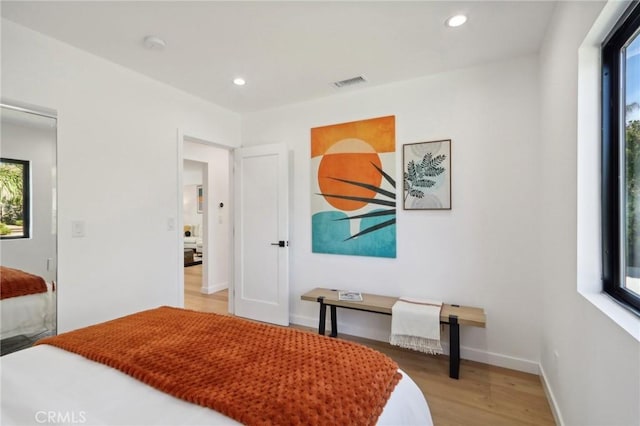 bedroom with light hardwood / wood-style floors and multiple windows