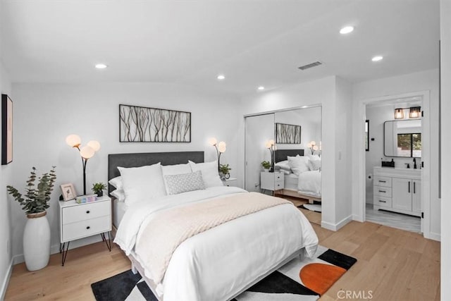 bedroom featuring a closet, vaulted ceiling, connected bathroom, and light hardwood / wood-style floors