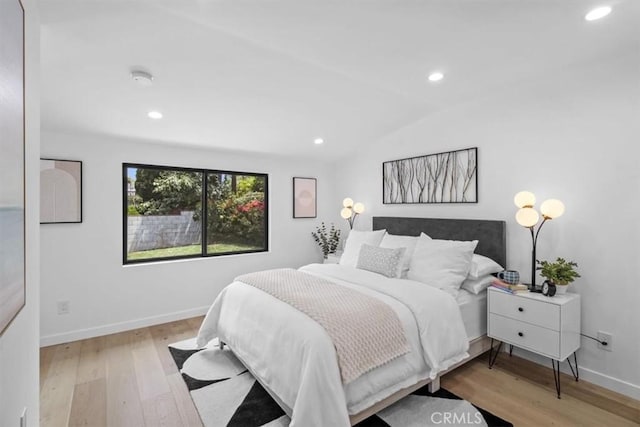 bedroom with light wood-type flooring and vaulted ceiling