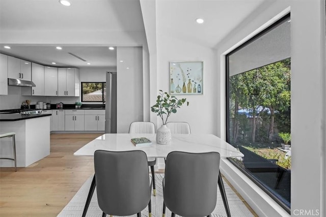 dining space with light hardwood / wood-style flooring and lofted ceiling