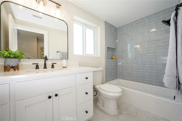 full bathroom featuring toilet, vanity, tile patterned floors, and tiled shower / bath