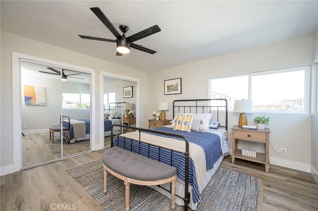 bedroom with ceiling fan, wood-type flooring, and multiple closets