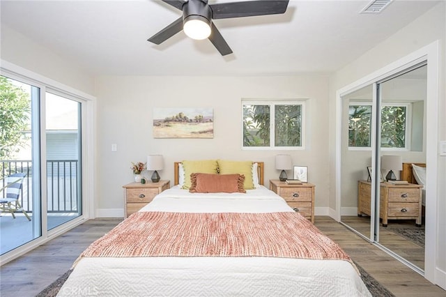 bedroom with ceiling fan, access to exterior, dark hardwood / wood-style floors, and a closet