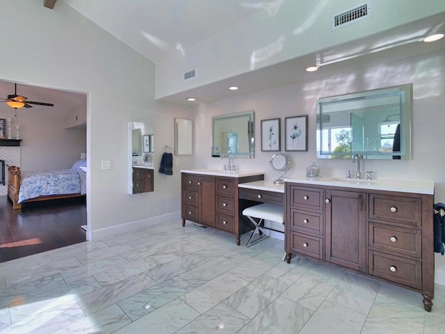 bathroom featuring ceiling fan, a fireplace, high vaulted ceiling, and vanity