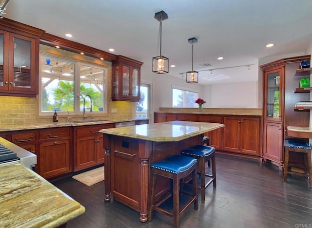 kitchen with decorative backsplash, decorative light fixtures, dark wood-type flooring, a kitchen island, and sink