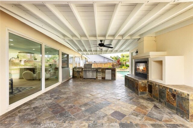 view of patio / terrace with ceiling fan, a multi sided fireplace, and area for grilling