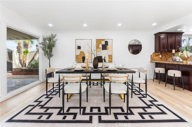 dining area with ornamental molding, a healthy amount of sunlight, and light hardwood / wood-style flooring