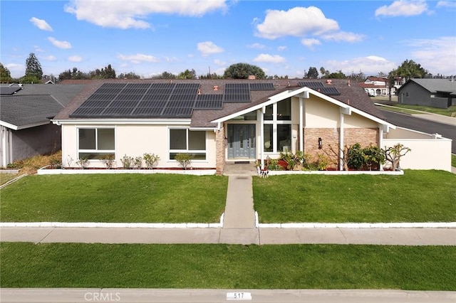 view of front of home with solar panels and a front yard