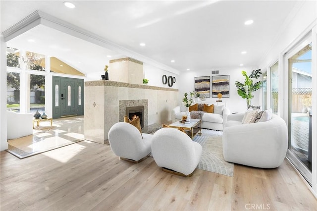 living room featuring vaulted ceiling, a high end fireplace, and light hardwood / wood-style flooring