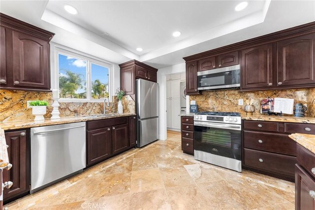 kitchen with tasteful backsplash, a tray ceiling, and stainless steel appliances