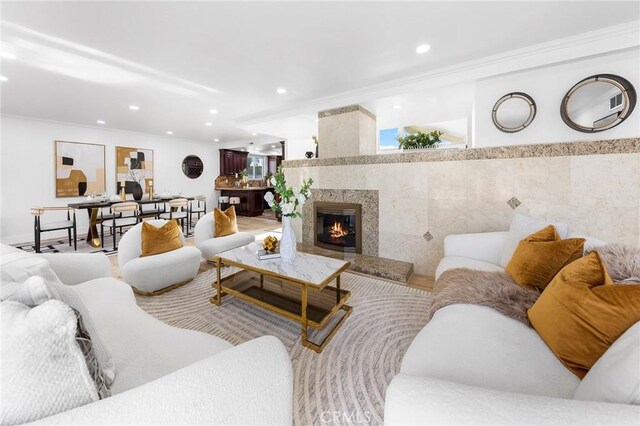 living room with tile walls, crown molding, and a tiled fireplace