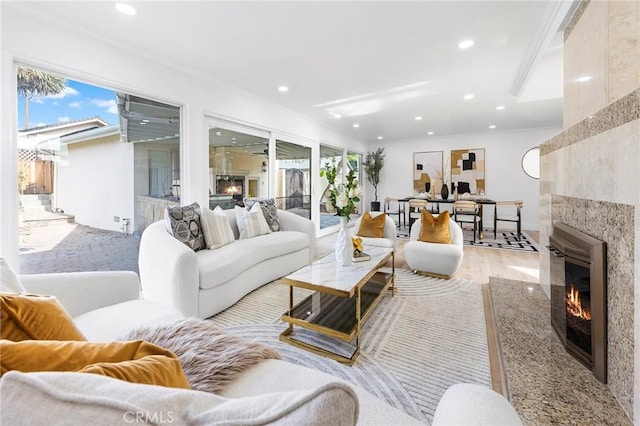 living room featuring light wood-type flooring, crown molding, and a fireplace