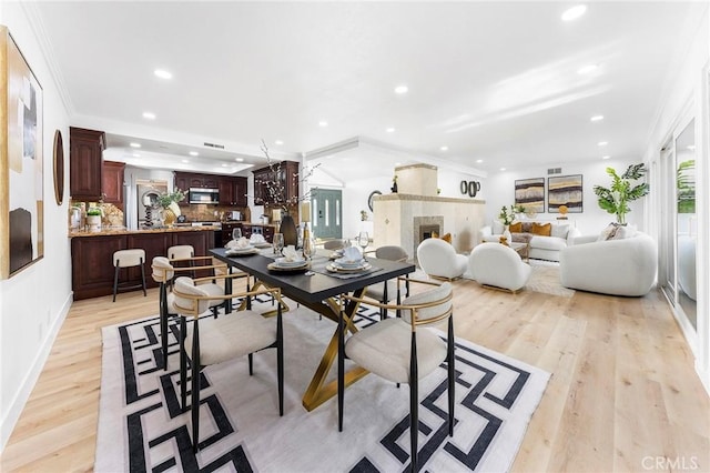 dining area with ornamental molding and light hardwood / wood-style floors