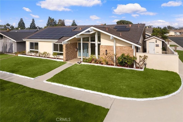 single story home with a front yard and solar panels